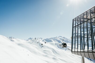 Schneebedeckte Berge und eine Seilbahn bei klarem Himmel.