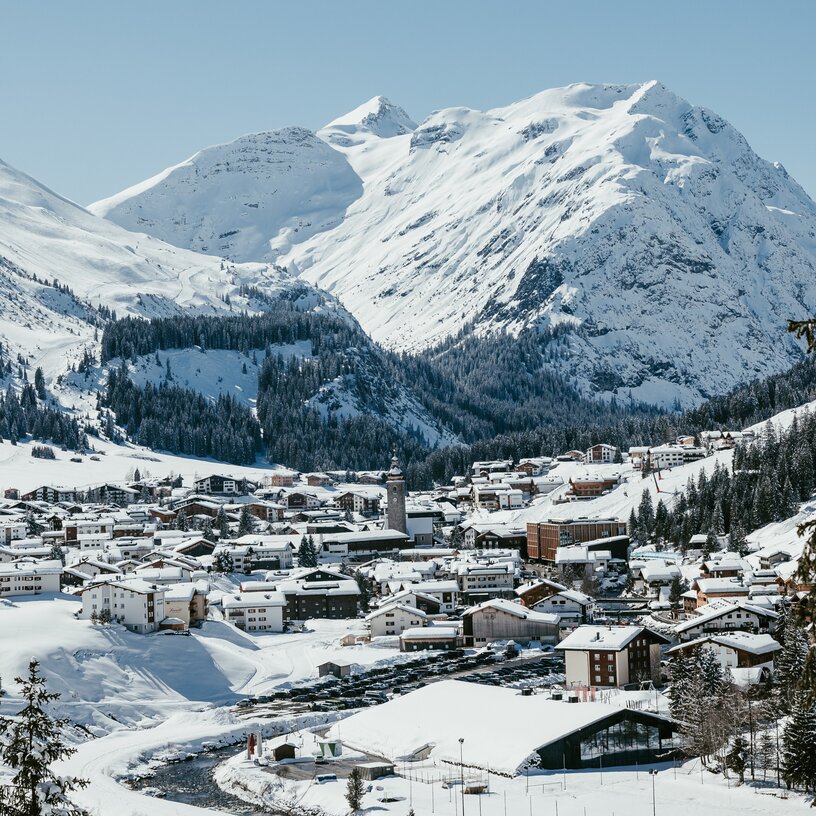 Das schneebedeckte Lech Zürs umgeben von hohen, verschneiten Bergen.