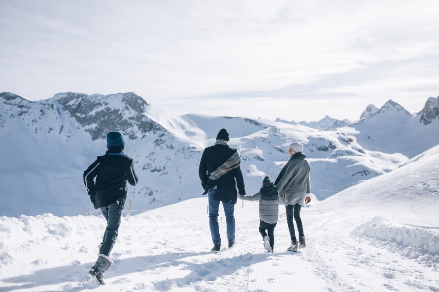 Vier Menschen wandern im Schnee in bergiger Landschaft.
