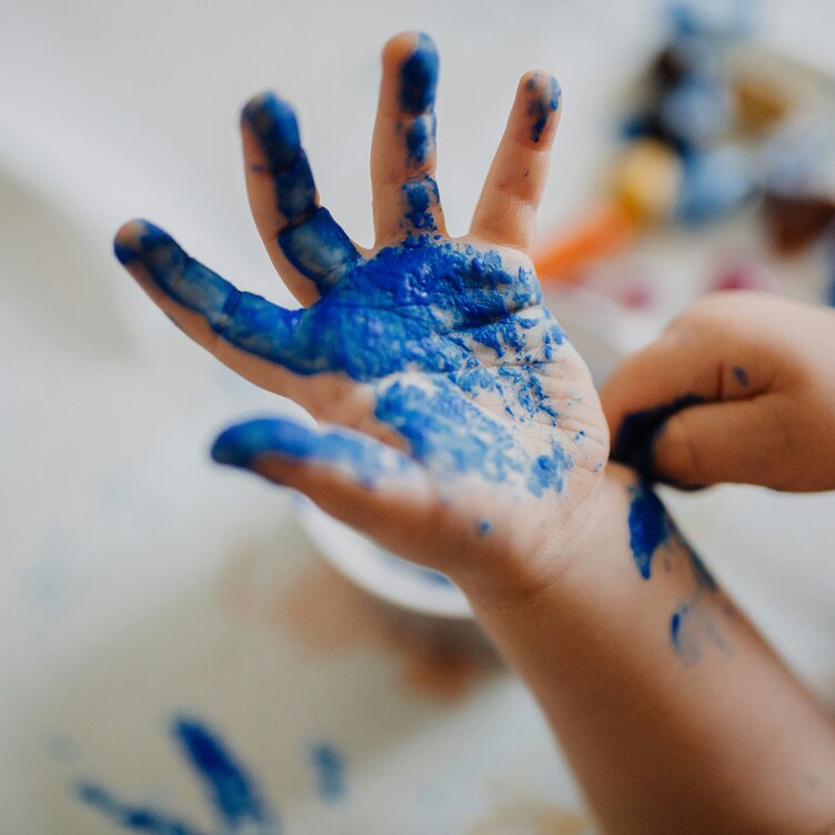 A child's hand covered in blue paint, close-up of the palm.