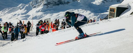 Skifahrer startet beim Weißen Ring-Rennen, Zuschauer und verschneite Berge im Hintergrund.