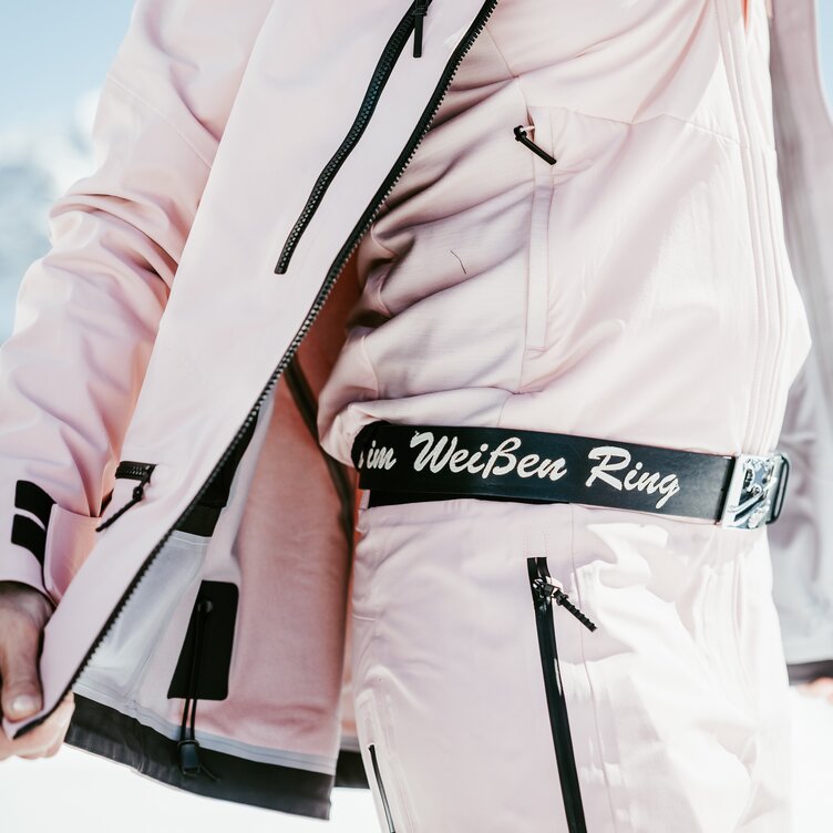 Person in pastellfarbener Skibekleidung mit auffälligem Gürtel.