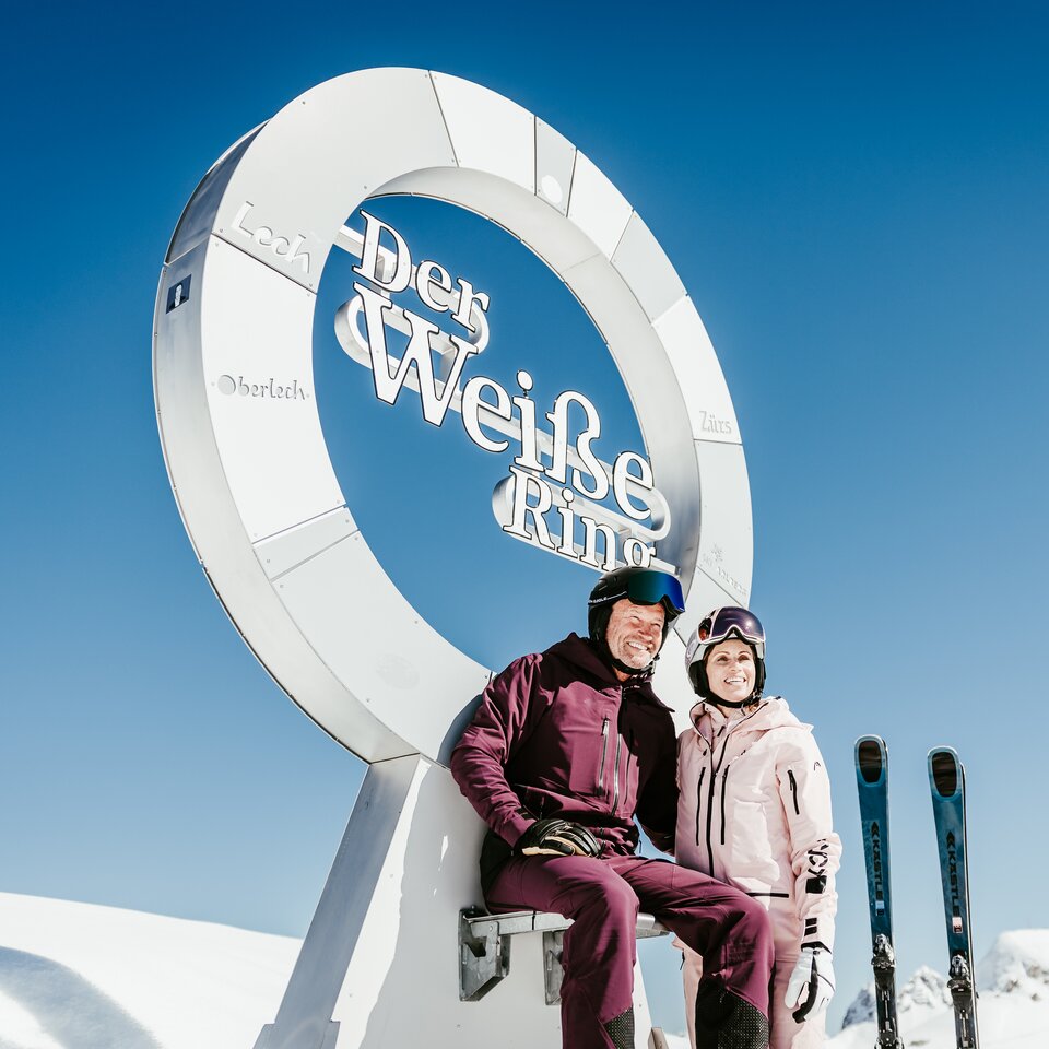 Zwei Personen posieren vor dem "Der Weiße Ring" Monument im Schnee.