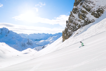 A skier descends a steep slope in the Alps.