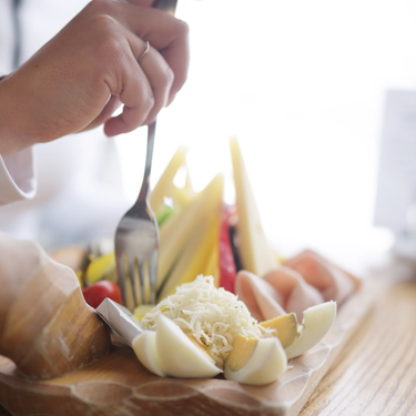 Cheese, eggs, and vegetables on a wooden board.