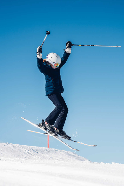 Skier takes off during a jump in a snowy landscape.