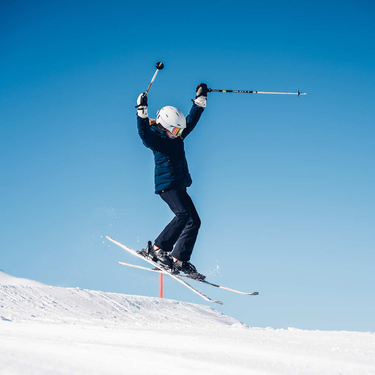 Skier takes off during a jump in a snowy landscape.