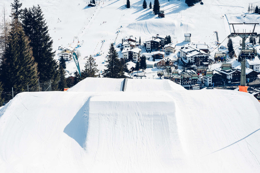 Schneeschanzen in einem Park mit Blick auf ein Bergdorf.