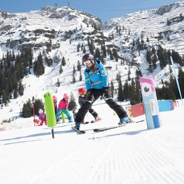 Children skiing in the mountains with an instructor.