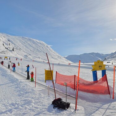 Children learning to ski in a sunny winter landscape.
