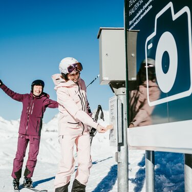 Two skiers happily posing for a photo at a photopoint.