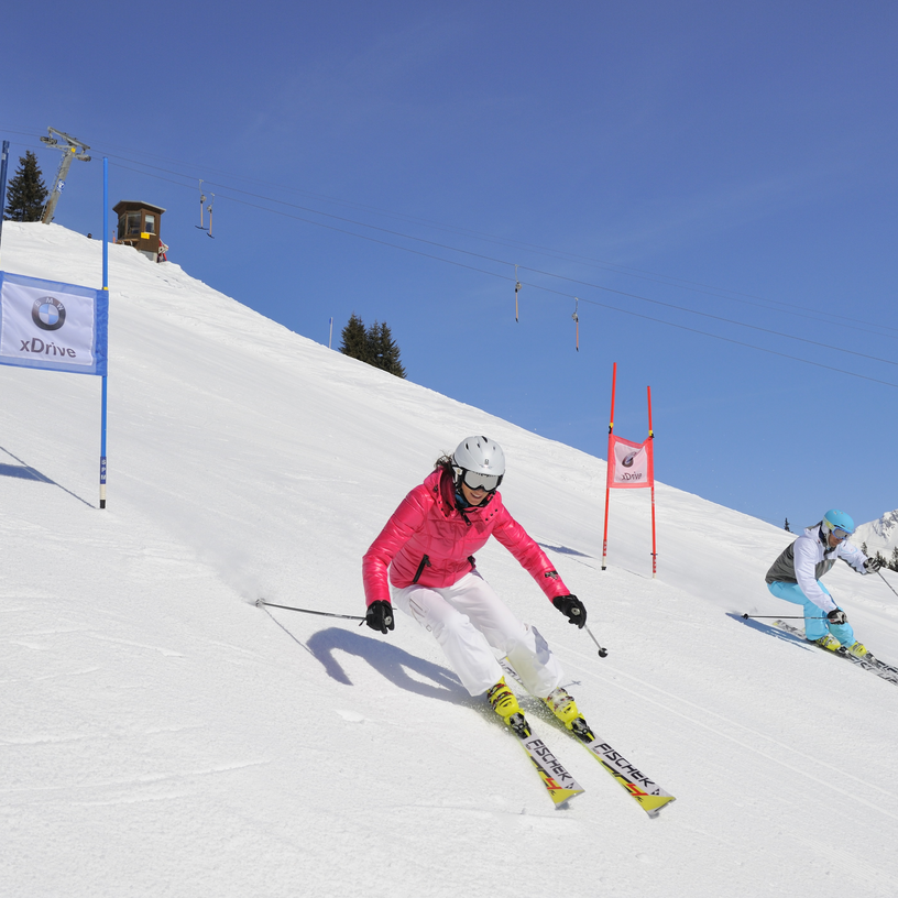 Two skiers in colorful gear racing down a marked slope.