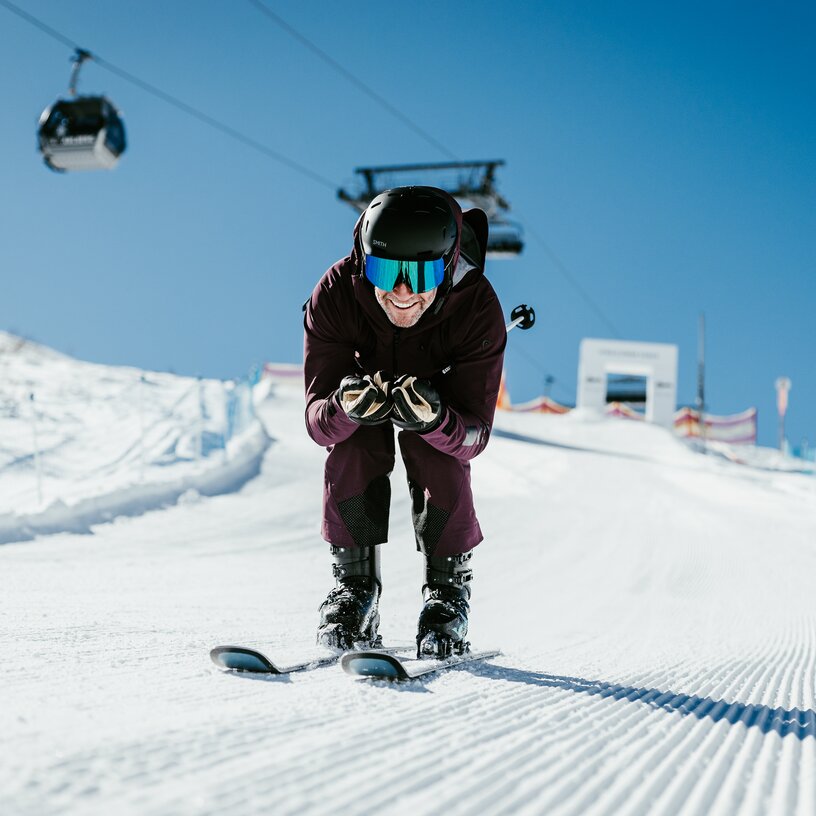 Man wearing helmet and goggles speeding on a ski slope.