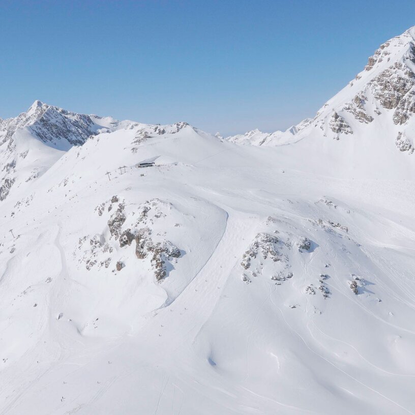 Luftaufnahme von schneebedeckten Bergen unter klarem Himmel.
