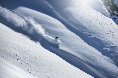 A skier going down a snow-covered slope.