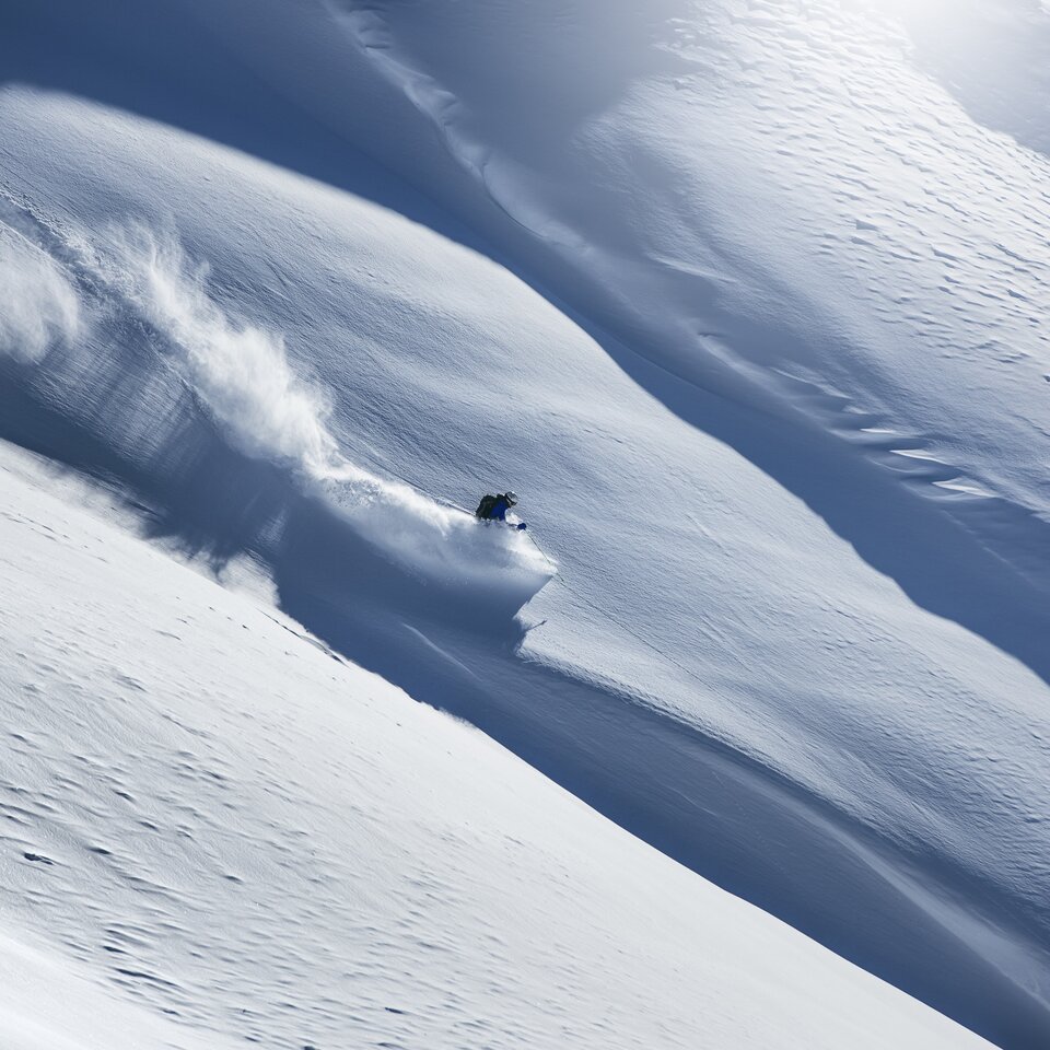 A skier going down a snow-covered slope.