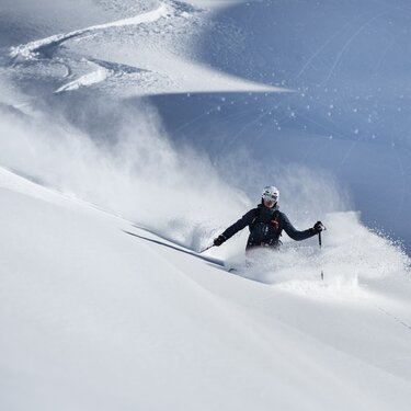 A skier navigating fresh powder on a mountain slope.