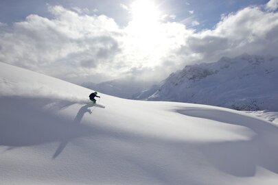 A skier gliding down a sunny, snowy mountain.