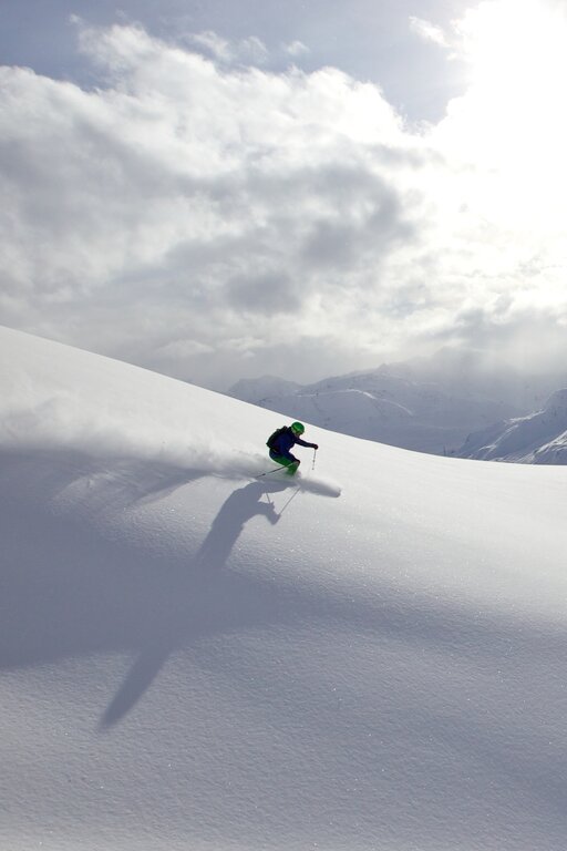 A skier gliding down a sunny, snowy mountain.