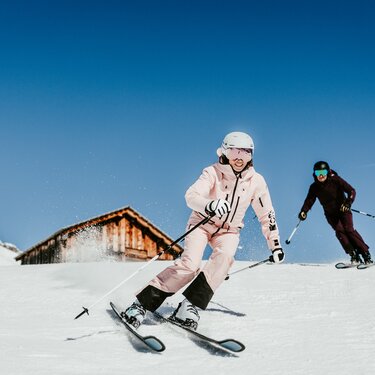 Two people skiing under a bright blue sky.