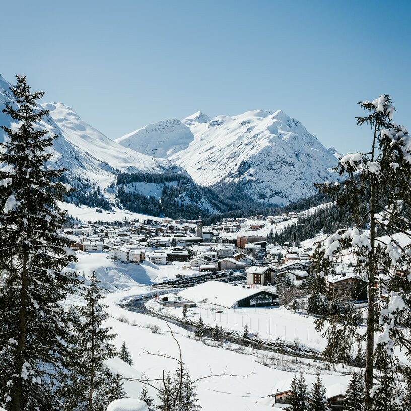 Das winterliche Dorf Lech Zürs am Arlberg eingerahmt von schneebedeckten Bergen und Wäldern.