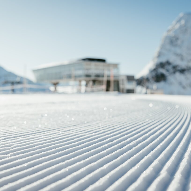 Perfekt präparierte Piste mit modernem Gebäude im Hintergrund in der Skiregion Lech Zürs.
