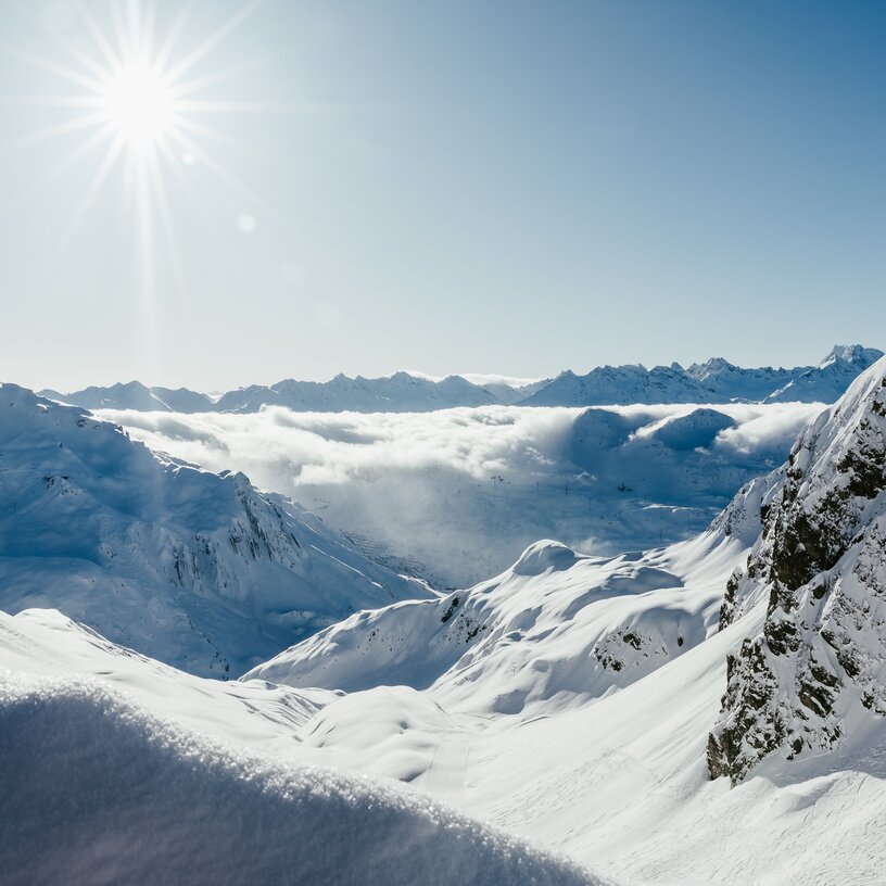 Snow-covered mountains and shining sun at Lech Zürs ski resort.