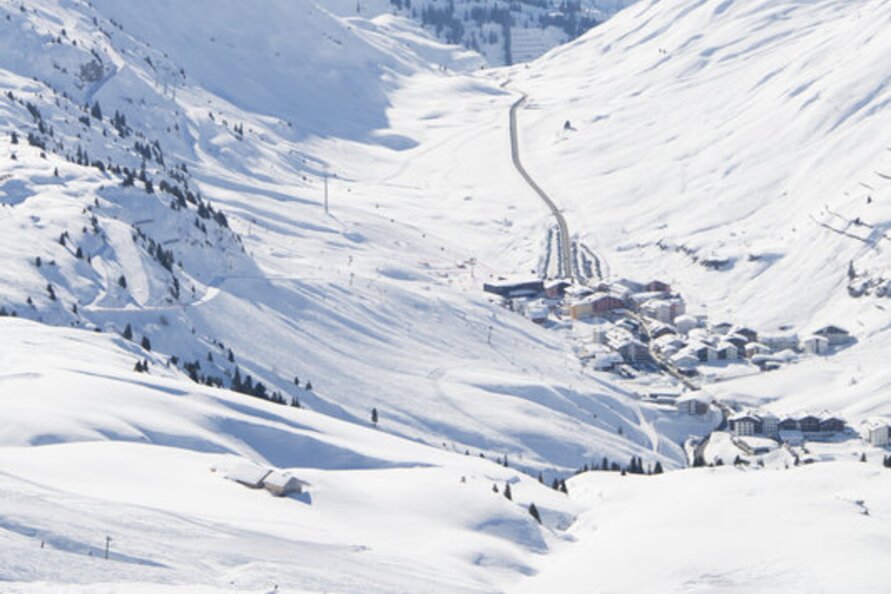 View of snowy mountains and Lech Zürs ski resort in sunlight.
