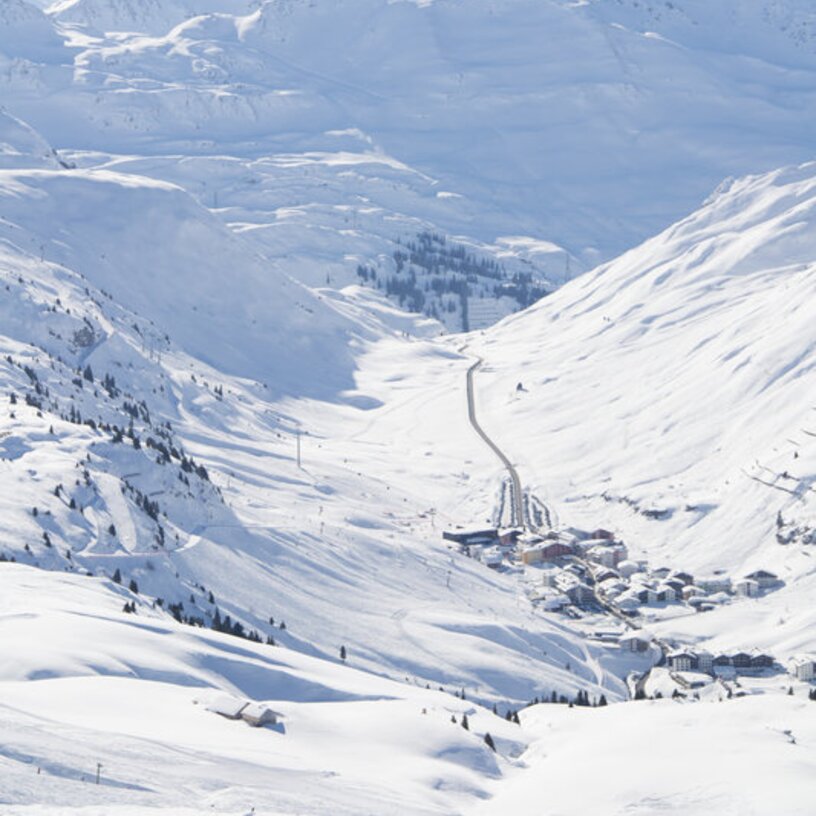 Blick auf verschneite Berge und Skiregion Lech Zürs im Sonnenschein.