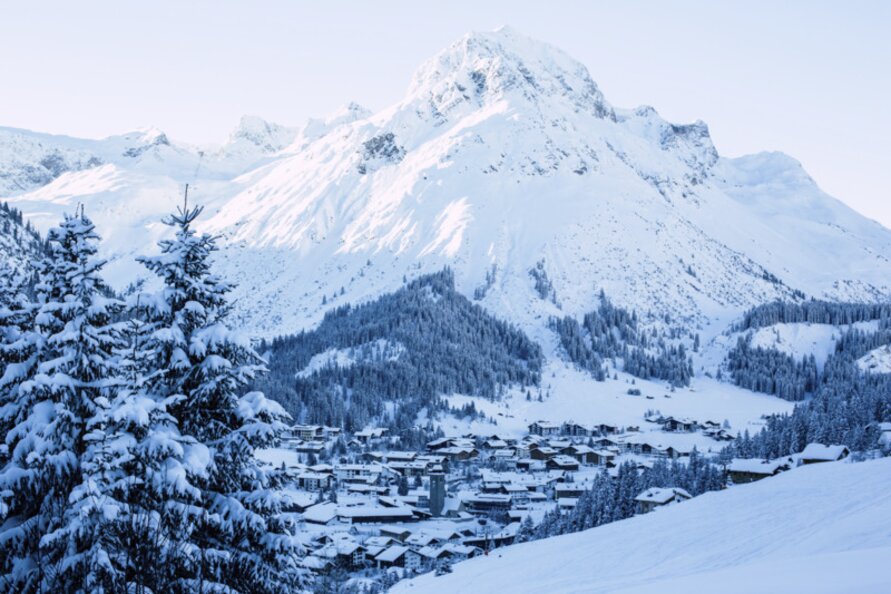 Snowy mountain landscape overlooking the village in Lech Zürs, surrounded by snow-covered trees.