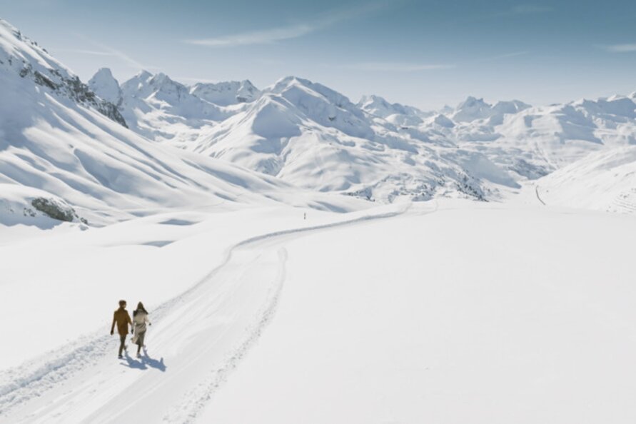 Two people walking through snowy landscape in Lech Zürs.