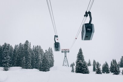 Cable cars passing through snow-covered trees at Lech Zürs ski resort.
