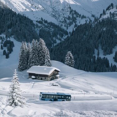 Snow-covered landscape with a bus and cabin at Lech Zürs ski resort.