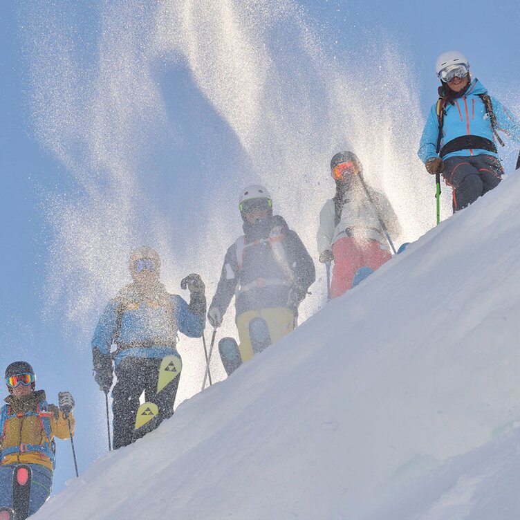 Group of skiers on a snowy slope under bright sunshine.