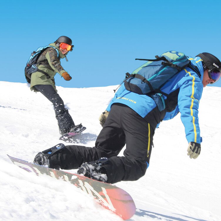Three people snowboarding down a snowy slope.