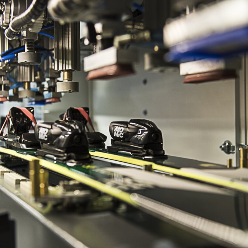 Close-up of a ski tuning machine with bindings on skis.