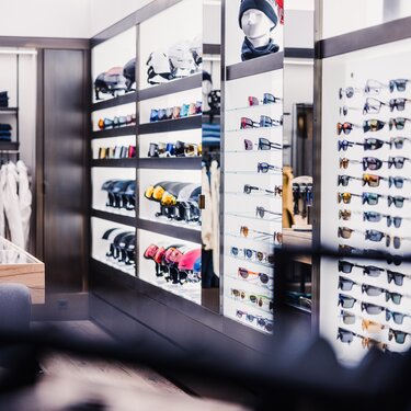 Shop with sunglasses and helmets in front of clothing racks.