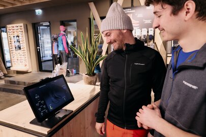 Two men interacting with a digital display in a sports shop.
