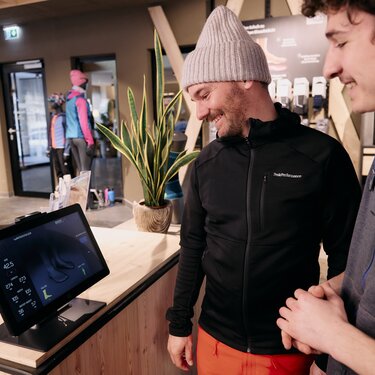 Two men interacting with a digital display in a sports shop.
