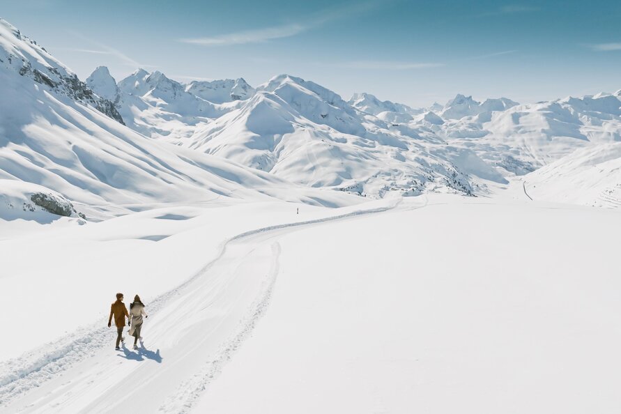 Ein Paar wandert auf einem verschneiten Weg in den Bergen.