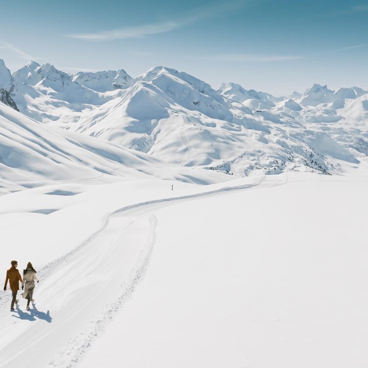 Ein Paar wandert auf einem verschneiten Weg in den Bergen.