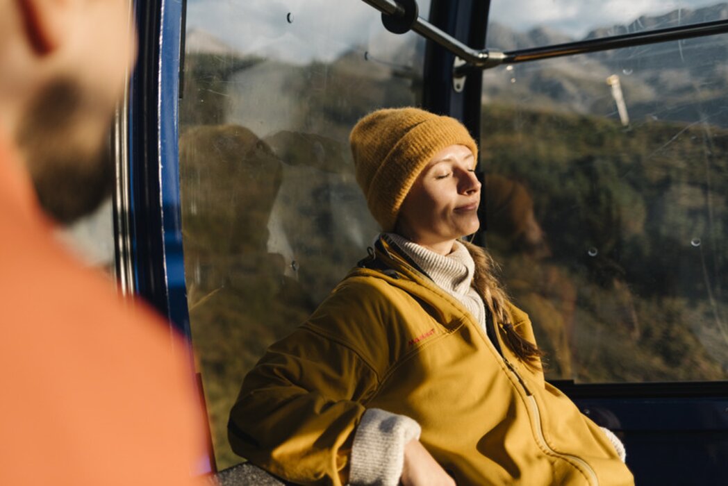 Person relaxing in cable car enjoying the sunshine.