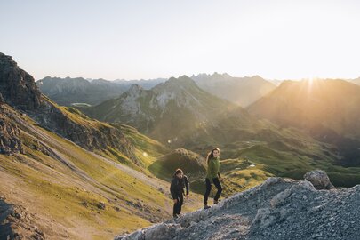 Two people hiking in mountainous terrain at sunrise.