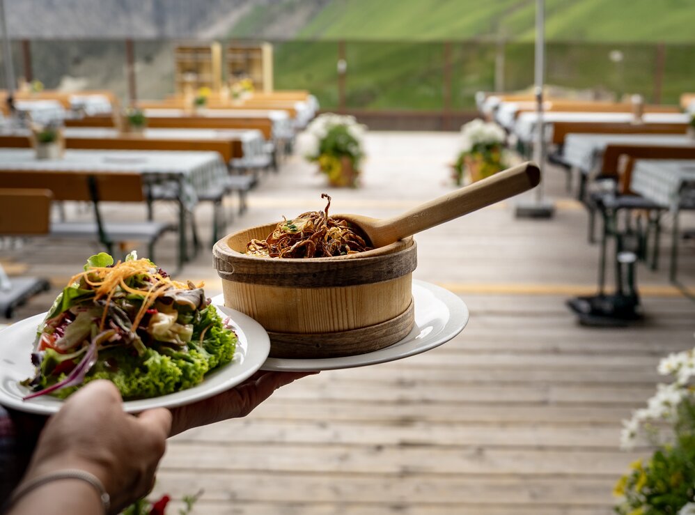 Traditional food being served on an Alpine sun terrace with mountain view.