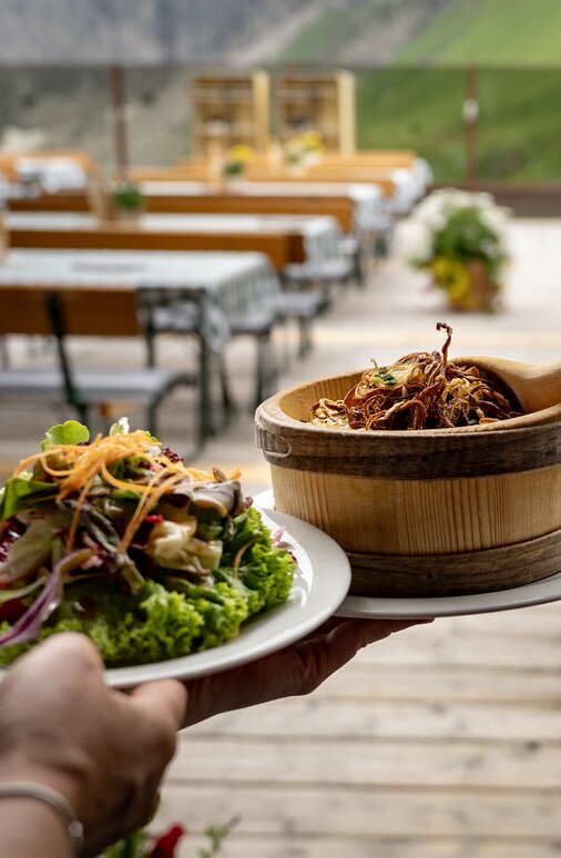 Traditional food being served on an Alpine sun terrace with mountain view.