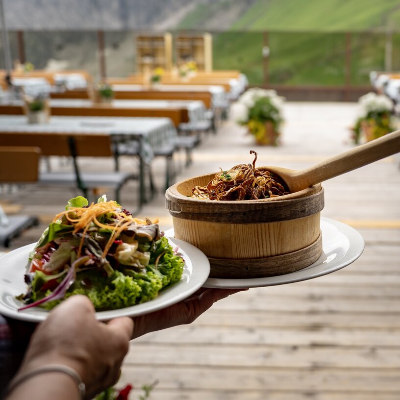Traditional food being served on an Alpine sun terrace with mountain view.