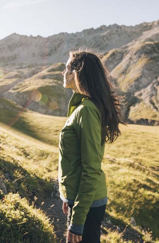Frau genießt die Aussicht auf einem sonnigen Bergpfad.