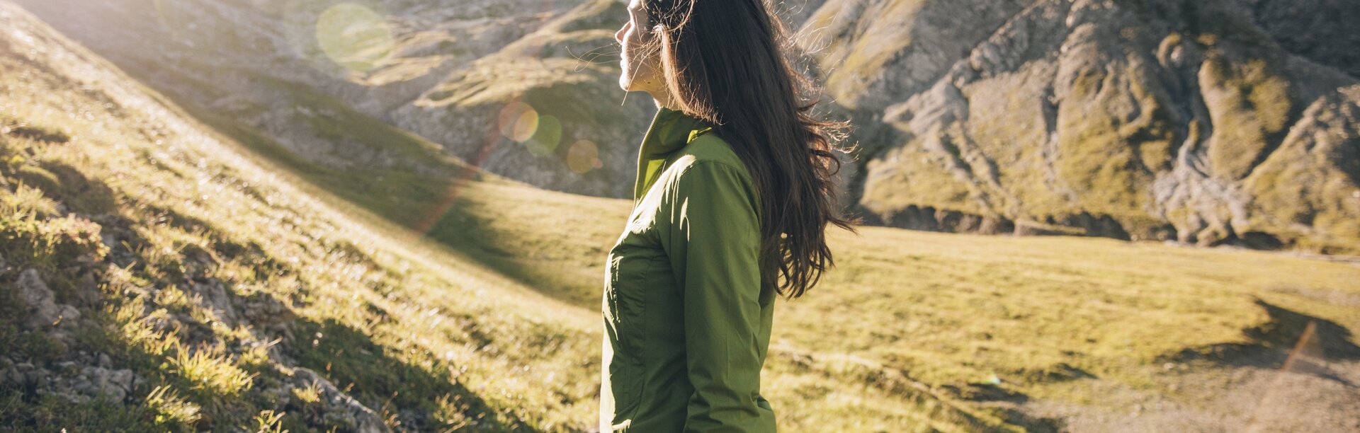 Frau genießt die Aussicht auf einem sonnigen Bergpfad.