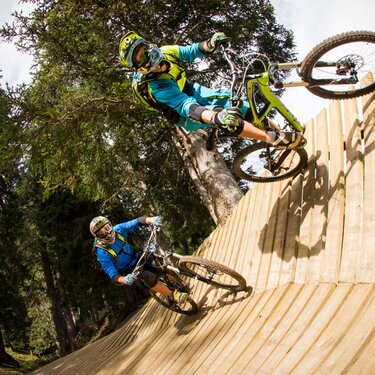 Two mountain bikers on a wooden ramp at Kriegerhorn family mountain.