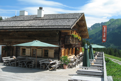 A wooden hut with a terrace and sun umbrellas on Kriegerhorn family mountain.